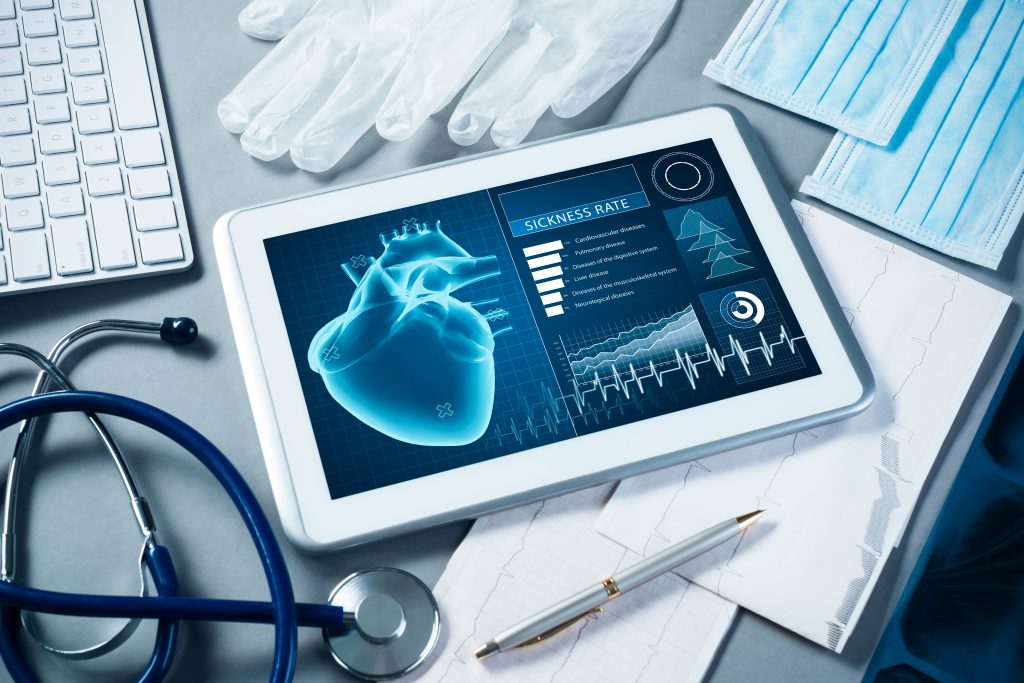 white tablet next to white gloves, blue surgical masks, stethoscope, and keyboard.